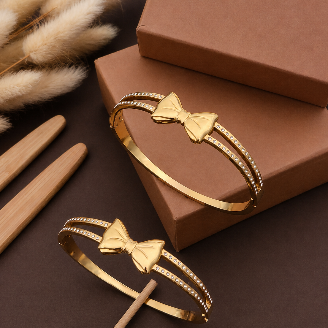 Gold bow-shaped bracelets on a brown surface with decorative elements.