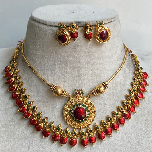 Gold necklace with red stones and matching earrings on a mannequin bust.